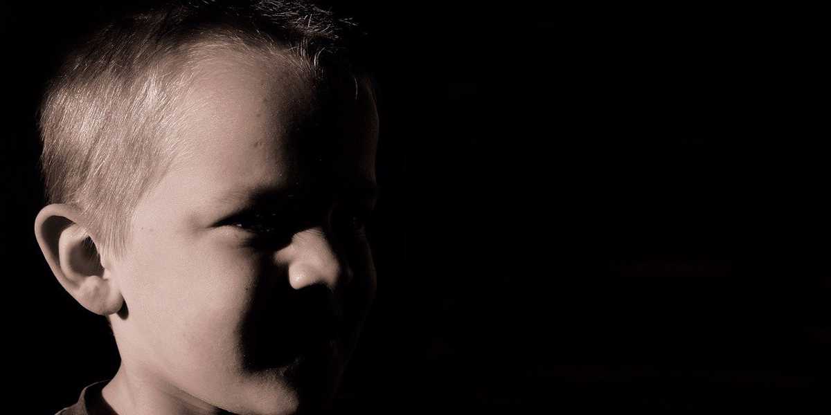 En pojke tittar åt sidan, ansiktet är mörkt